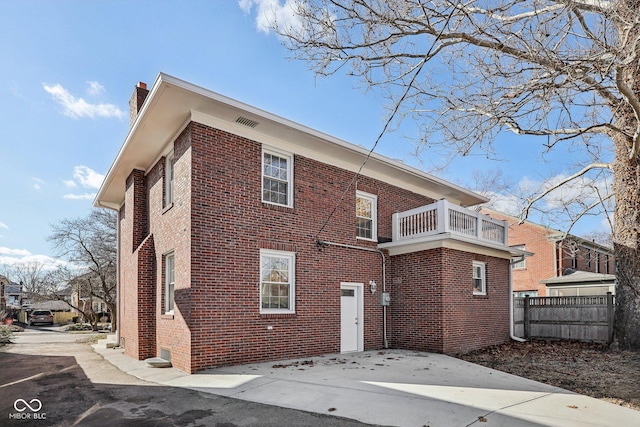 3645 N Delaware St, Indianapolis, IN 46205 - back of property featuring brick siding, a chimney, a balcony, and fence