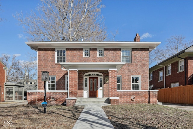 view of front of house with fence, brick siding, and a chimney