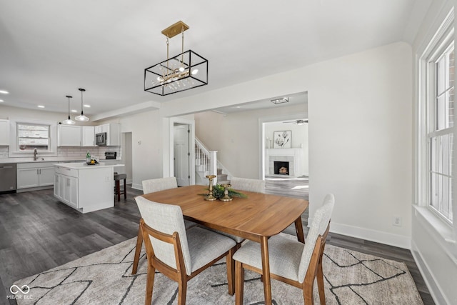 3645 N Delaware St, Indianapolis, IN 46205 - dining space with stairway, a fireplace with raised hearth, baseboards, and dark wood-style flooring