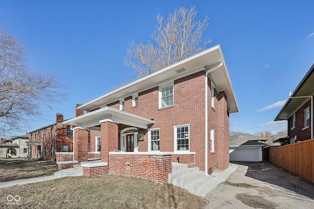 view of front facade featuring an outbuilding, brick siding, and fence