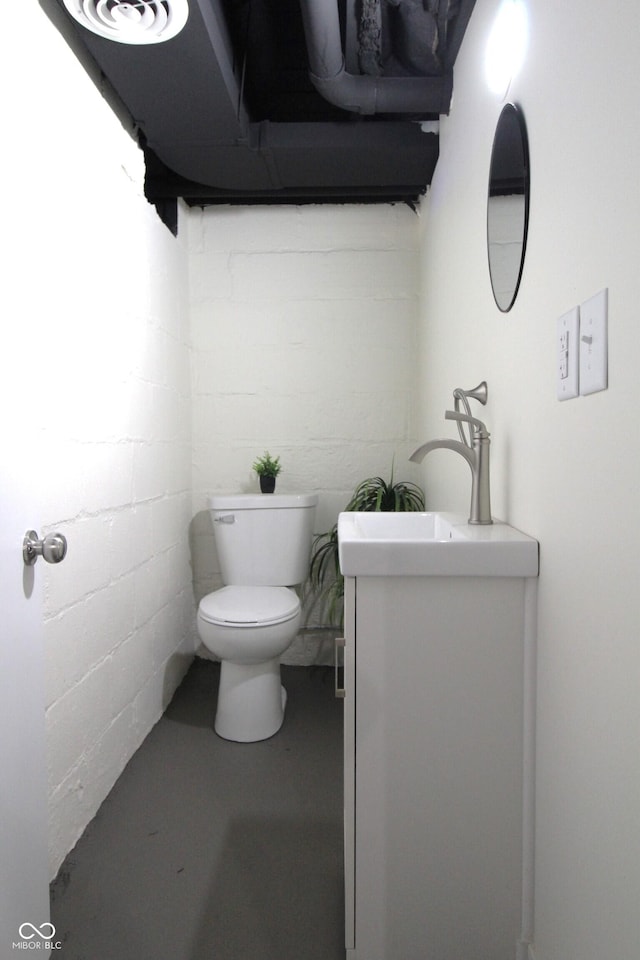 3645 N Delaware St, Indianapolis, IN 46205 - bathroom featuring vanity, concrete block wall, toilet, and concrete floors