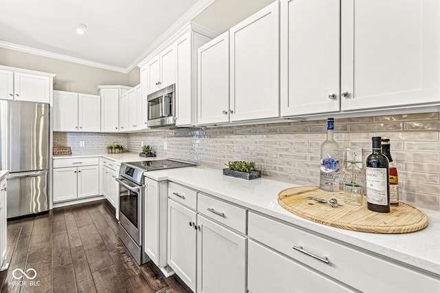 kitchen featuring white cabinetry, light countertops, appliances with stainless steel finishes, decorative backsplash, and crown molding