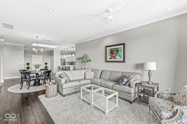 living area with ornamental molding, dark wood-type flooring, ceiling fan with notable chandelier, and visible vents