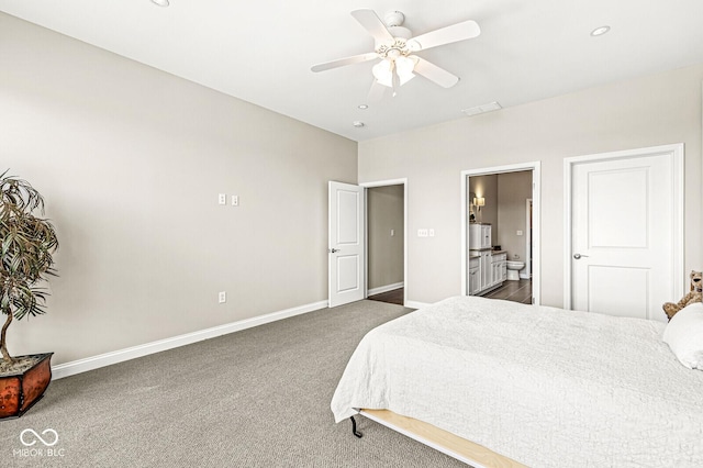 bedroom with ceiling fan, ensuite bath, baseboards, and dark carpet