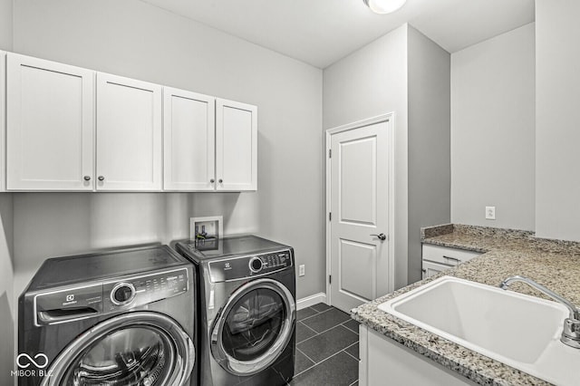 laundry area featuring dark tile patterned flooring, a sink, baseboards, cabinet space, and washing machine and clothes dryer