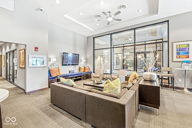 carpeted living room featuring ceiling fan, a tray ceiling, a towering ceiling, and baseboards