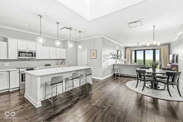 kitchen featuring a center island with sink, appliances with stainless steel finishes, light countertops, and backsplash