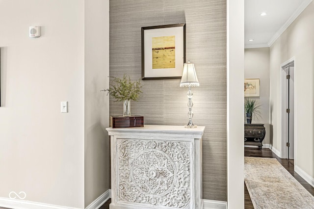 hallway featuring recessed lighting, an accent wall, ornamental molding, baseboards, and wallpapered walls