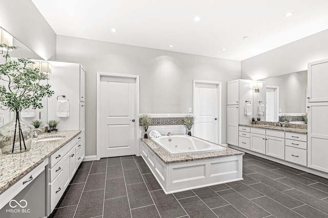 bathroom with two vanities, a sink, and a tub with jets