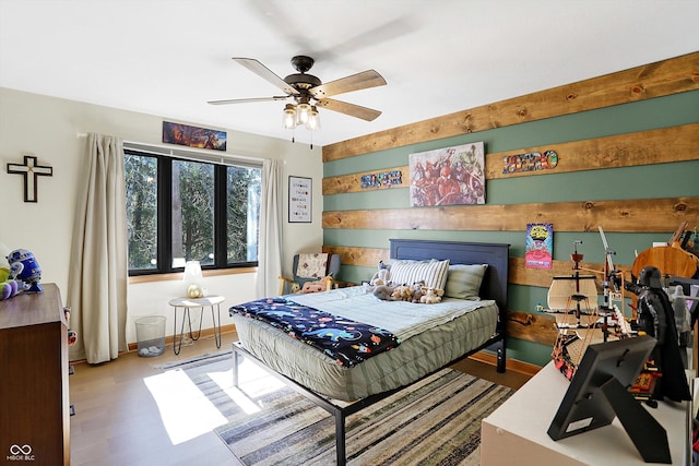 bedroom with a ceiling fan, wood finished floors, and baseboards