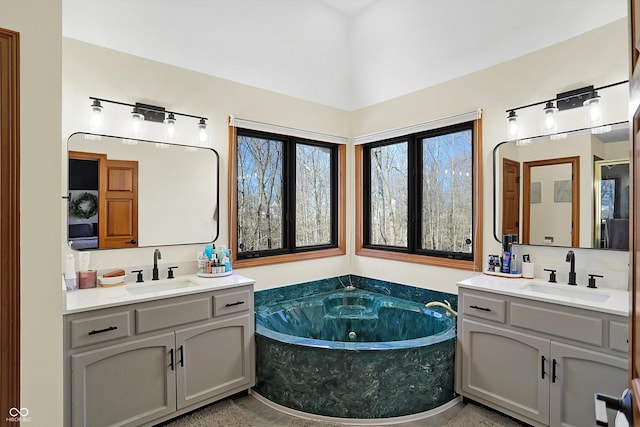 full bath featuring two vanities, a bath, and a sink