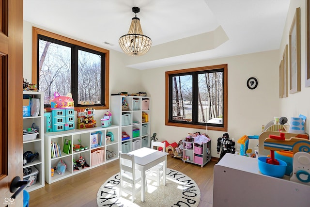 rec room with visible vents, a healthy amount of sunlight, wood finished floors, and an inviting chandelier