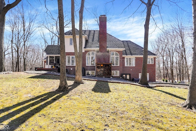 view of front of house featuring a front lawn, brick siding, and a chimney