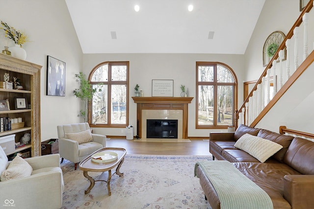 living area with stairway, plenty of natural light, wood finished floors, and a fireplace with flush hearth