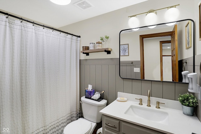 full bathroom with vanity, a shower with shower curtain, a wainscoted wall, visible vents, and toilet