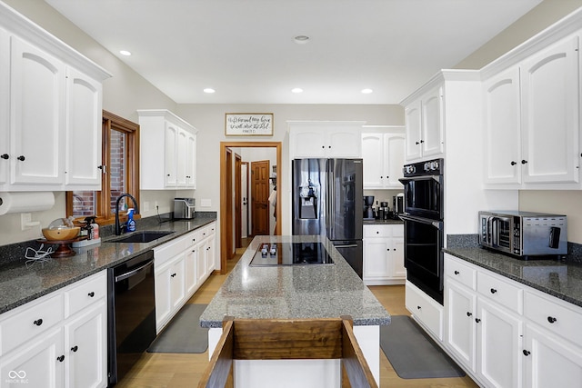 kitchen with recessed lighting, white cabinetry, black appliances, and a sink