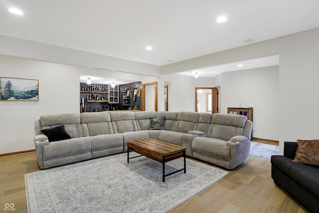 living area featuring bar, recessed lighting, light wood-type flooring, and baseboards