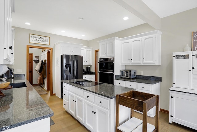 kitchen featuring light wood-type flooring, recessed lighting, white cabinets, black appliances, and a sink