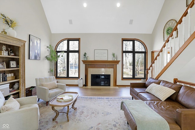 living room with a healthy amount of sunlight, wood finished floors, stairs, and a tile fireplace