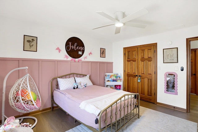 bedroom featuring wainscoting, a ceiling fan, and wood finished floors