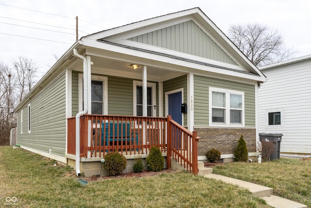 view of front facade with a porch, board and batten siding, and a front lawn