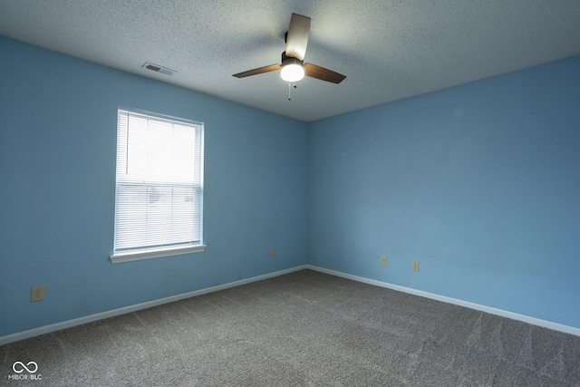 empty room with carpet floors, visible vents, ceiling fan, a textured ceiling, and baseboards