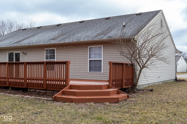 rear view of house with roof with shingles, a lawn, and a wooden deck