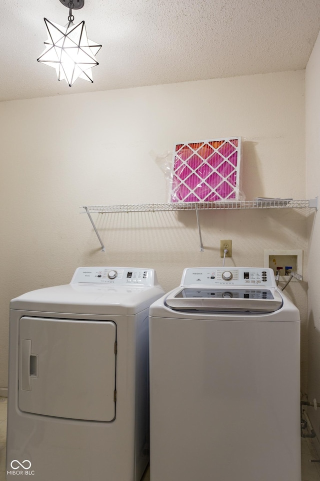 washroom with laundry area, washer and clothes dryer, and a textured ceiling