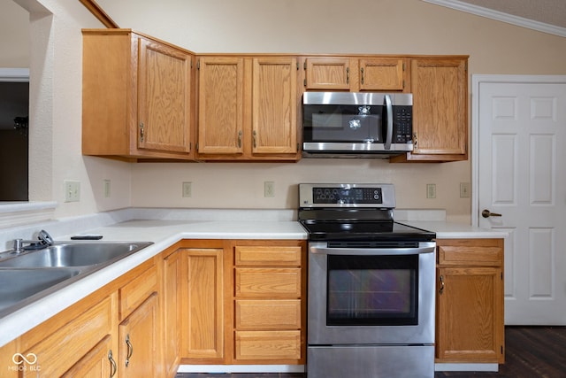 kitchen featuring a sink, vaulted ceiling, light countertops, appliances with stainless steel finishes, and crown molding