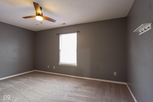 carpeted spare room featuring visible vents, ceiling fan, a textured ceiling, and baseboards