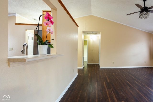 interior space featuring lofted ceiling, ornamental molding, a textured ceiling, wood finished floors, and baseboards