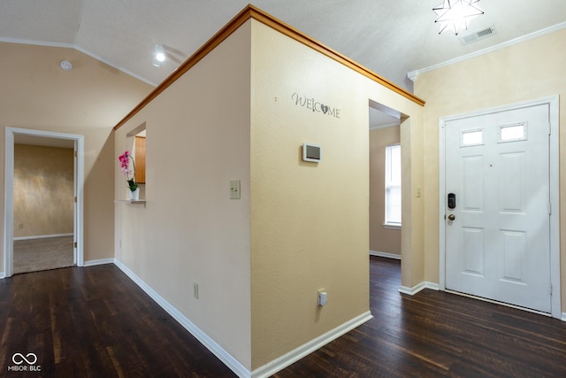 foyer featuring baseboards, visible vents, lofted ceiling, ornamental molding, and wood finished floors