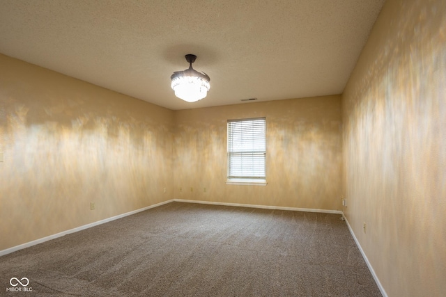 unfurnished room with a textured ceiling, carpet flooring, visible vents, and baseboards