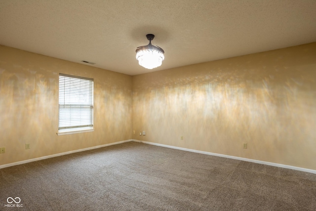 spare room featuring a textured ceiling, carpet flooring, visible vents, and baseboards