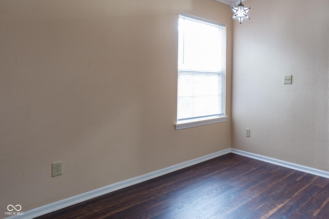 spare room featuring dark wood-style floors and baseboards