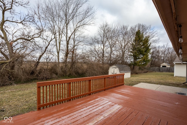 deck with a lawn, an outdoor structure, fence, and a shed