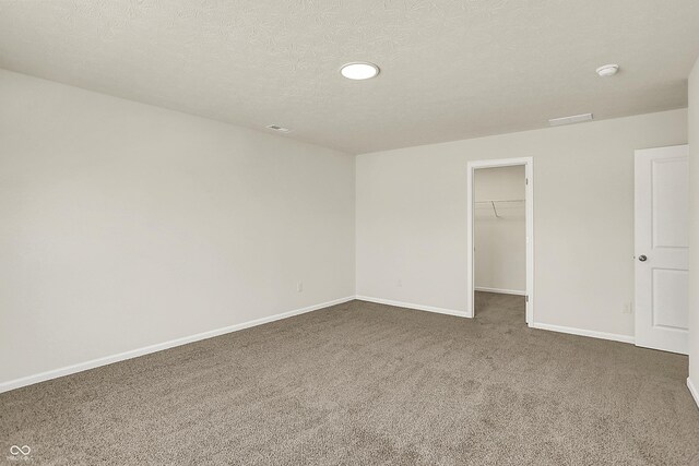 7168 Jackson Dr, Cumberland, IN 46229 - unfurnished bedroom featuring a walk in closet, baseboards, a closet, a textured ceiling, and dark colored carpet