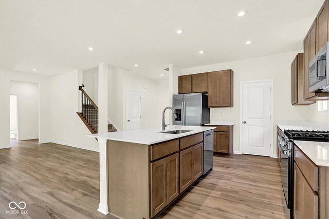 7168 Jackson Dr, Cumberland, IN 46229 - kitchen featuring appliances with stainless steel finishes, light wood-type flooring, a kitchen island with sink, light countertops, and recessed lighting