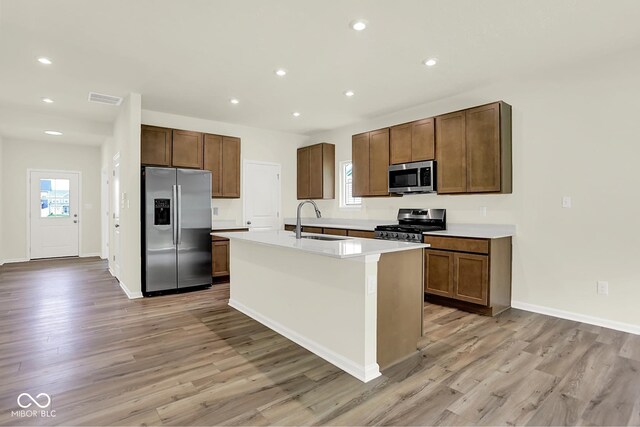 7168 Jackson Dr, Cumberland, IN 46229 - kitchen featuring stainless steel appliances, light wood-style floors, recessed lighting, a center island with sink, and light countertops