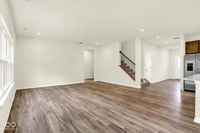 7168 Jackson Dr, Cumberland, IN 46229 - unfurnished living room with stairway, wood finished floors, and recessed lighting