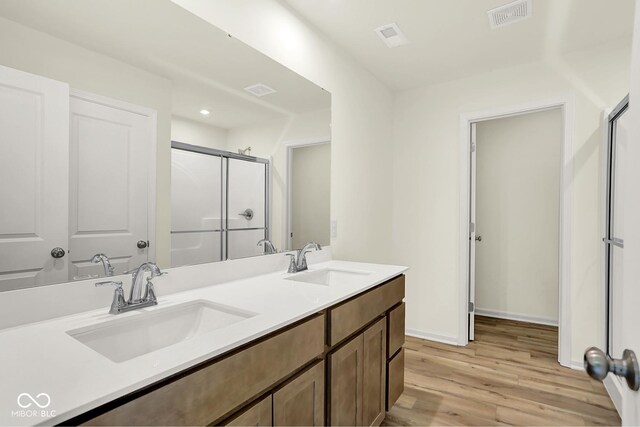 7168 Jackson Dr, Cumberland, IN 46229 - bathroom featuring double vanity, a stall shower, and wood finished floors