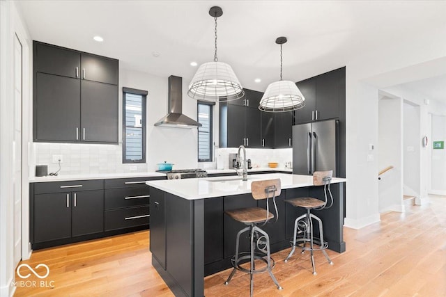 2026 Alvord St, Indianapolis, IN 46202 - kitchen featuring light countertops, freestanding refrigerator, wall chimney range hood, and dark cabinets