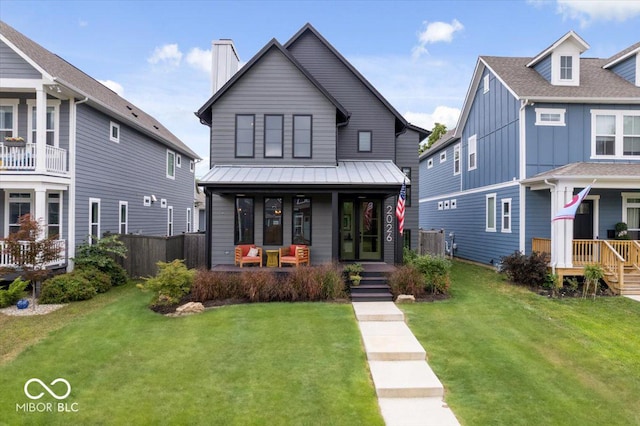 2026 Alvord St, Indianapolis, IN 46202 - view of front of house featuring board and batten siding, a front lawn, fence, covered porch, and a chimney