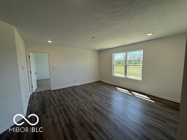 spare room featuring recessed lighting, baseboards, a textured ceiling, and dark wood-style floors