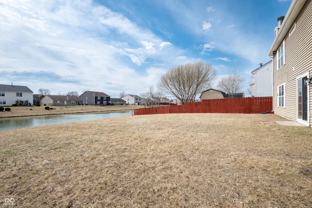 view of yard featuring a water view, fence, and a residential view