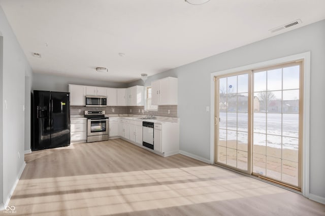 kitchen featuring light wood finished floors, tasteful backsplash, visible vents, appliances with stainless steel finishes, and light countertops