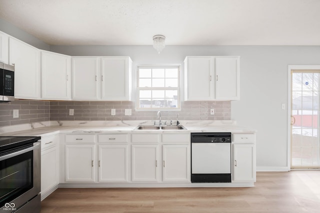 kitchen featuring backsplash, stainless steel appliances, a sink, and light wood finished floors