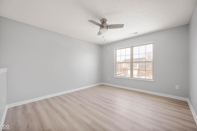 spare room featuring visible vents, ceiling fan, a textured ceiling, light wood-type flooring, and baseboards