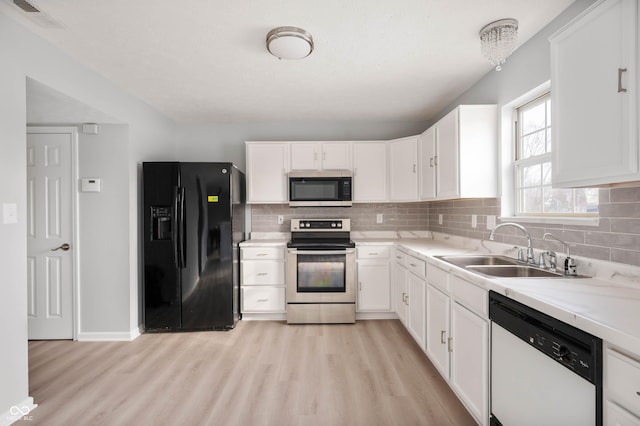 kitchen featuring appliances with stainless steel finishes, white cabinets, visible vents, and a sink