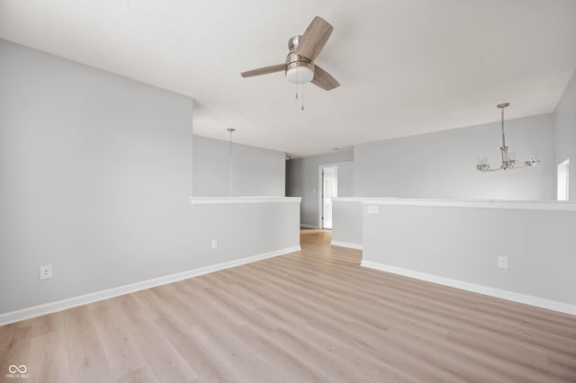 empty room with light wood-style floors, baseboards, and ceiling fan with notable chandelier